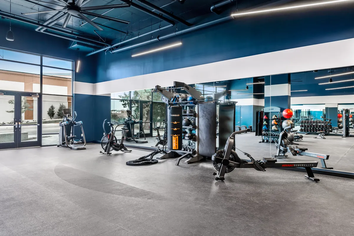 Modern fitness center with state-of-the-art exercise equipment, large windows for natural light, and a sleek design.