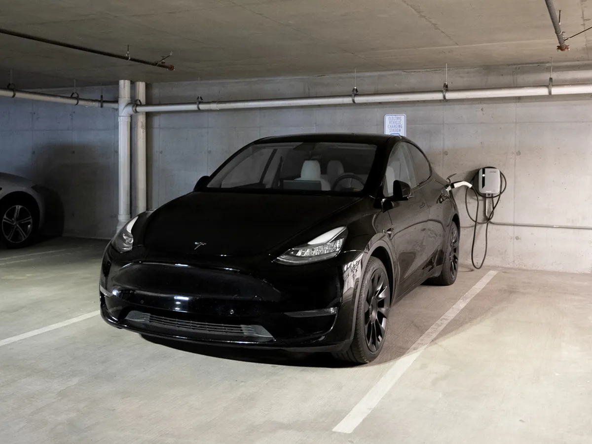 Modern underground parking space featuring a sleek black electric vehicle charging at a designated station, showcasing eco-friendly living.