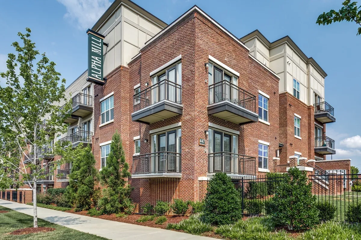 Charming brick apartment building in Charlotte, NC with spacious balconies and lush greenery, offering modern urban living in a vibrant community.