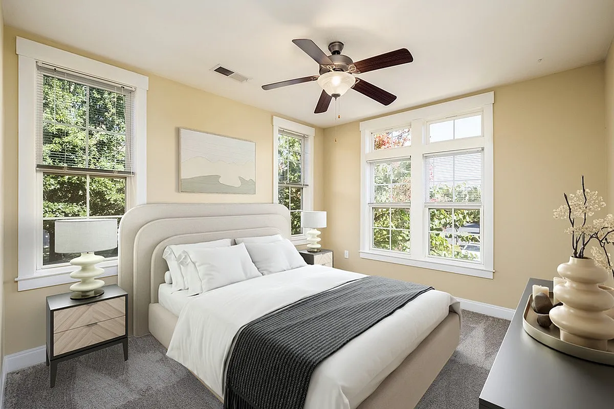 Bright and airy bedroom at Alpha Mill Apartments  with large windows, elegant ceiling fan, and stylish decor.