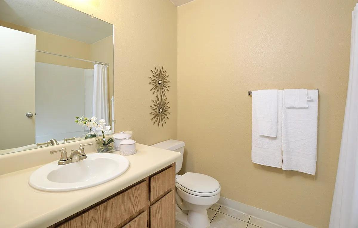 Cozy bathroom at Camelot Apartments with modern fixtures, fresh white towels, decorative wall art, and elegant vanity accents.