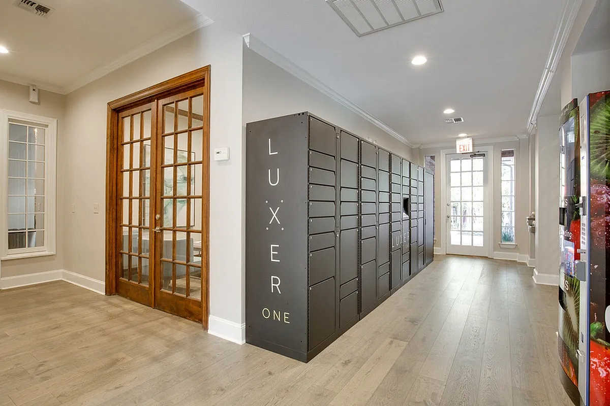 Modern apartment clubhouse at Raveneaux Apartments with sleek Luxer One package lockers and elegant wooden doors, offering a bright and welcoming atmosphere.
