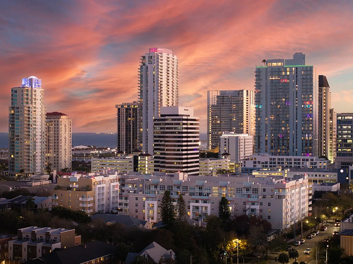 Stunning urban skyline at sunset, showcasing modern high-rise apartments and city lights with a vibrant ocean backdrop from Cottonwood Bayview.