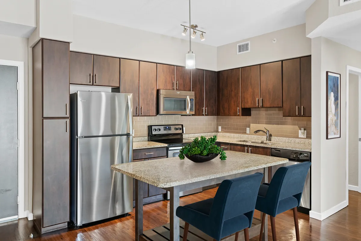 Modern kitchen design at Cottonwood Bayview with sleek stainless steel appliances, elegant dark wood cabinets, and a stylish granite island with seating for two.