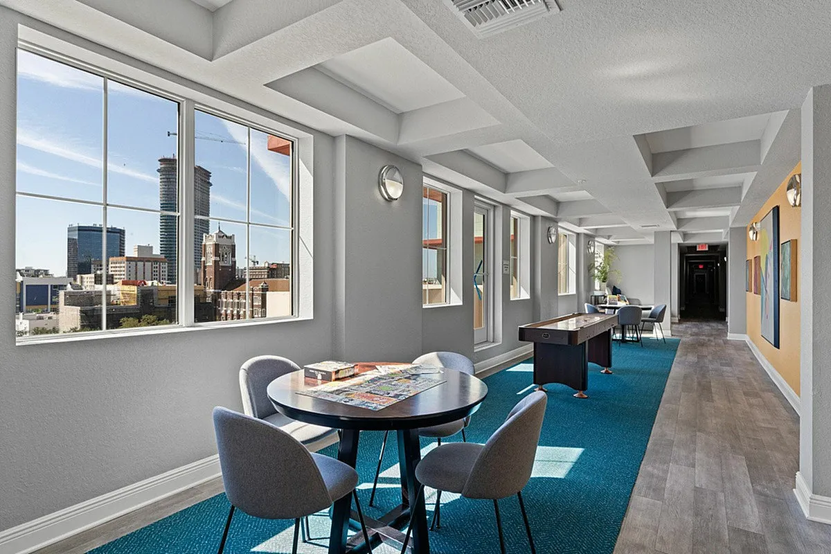 Cottonwood Bayview's bright and modern recreational area with game table and stunning city views through large windows.