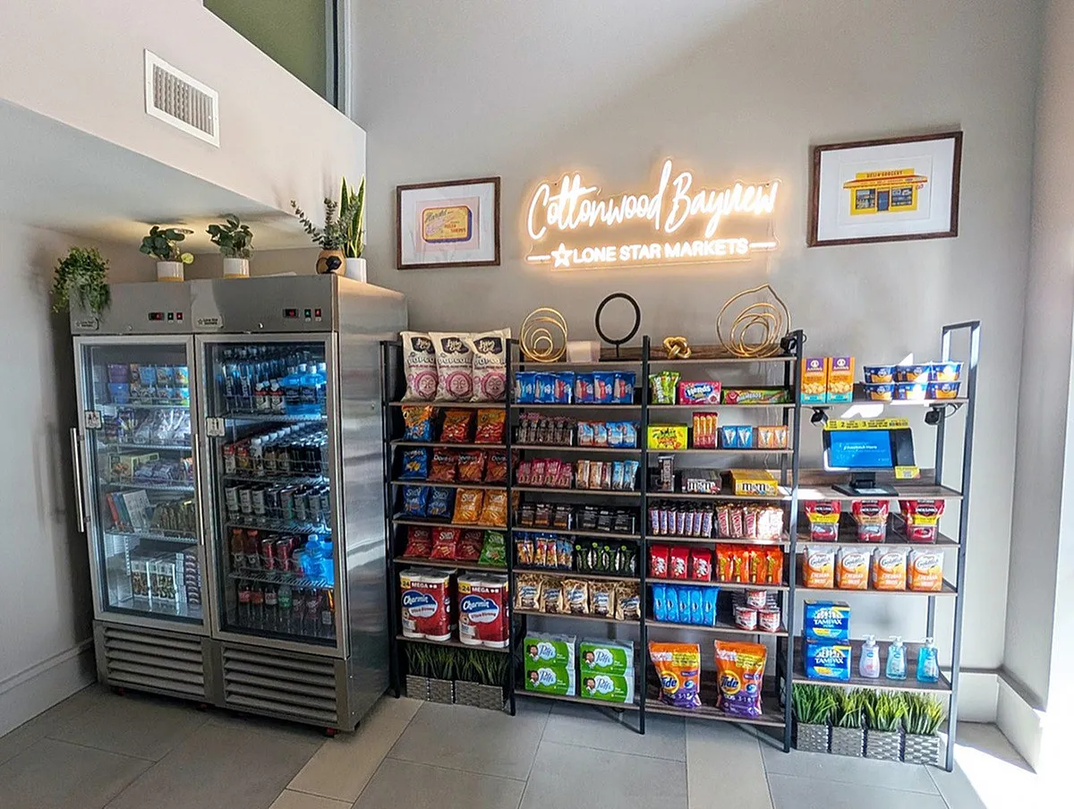 Inviting convenience corner with stocked snack shelves, vibrant drinks coolers, and modern decor at Cottonwood Bayview Apartments.