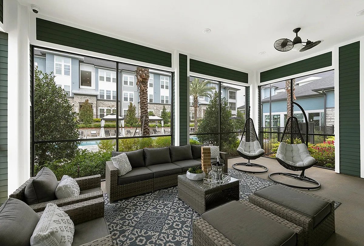 Inviting screened patio at Cottonwood Clermont with plush seating, modern hanging chairs, and a view of the lush garden and pool area, perfect for relaxation.