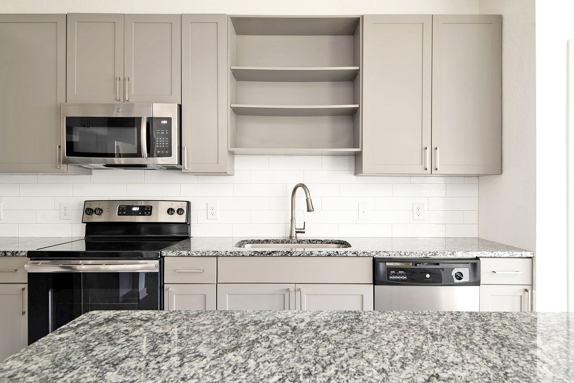 Modern kitchen at Cottonwood Clermont with sleek stainless steel appliances, elegant granite countertops, and ample cabinet space.