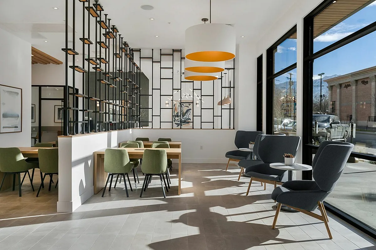 Modern coworking space at Cottonwood Highland Apartments with stylish seating, large windows, and elegant lighting, ideal for social gatherings or casual meetings.