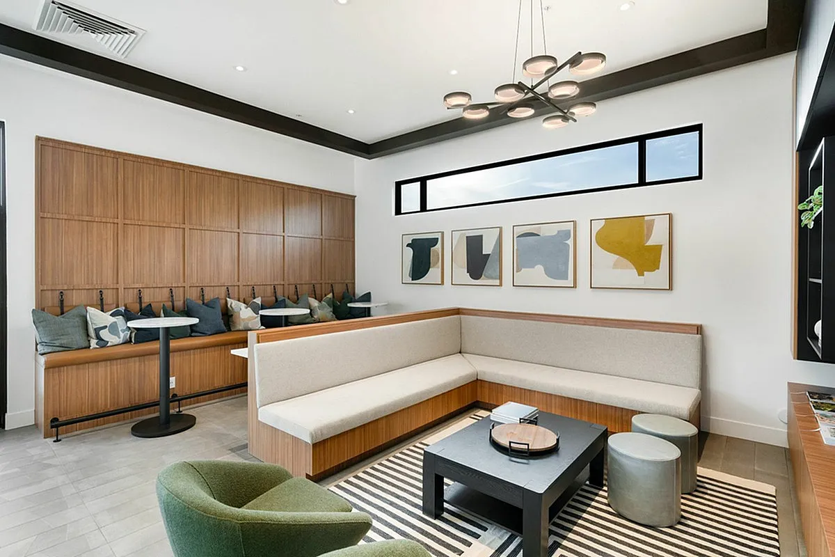 Modern, elegant living space in Cottonwood Highland Apartments clubroom with a chic sectional sofa, unique abstract art, and a stylish coffee table adorned with vibrant decor.