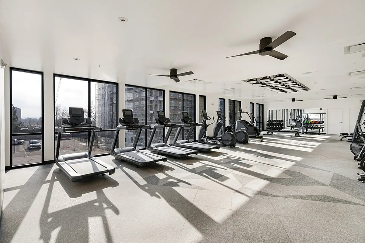 Bright, modern fitness center at Cottonwood Highland Apartments with state-of-the-art equipment and large windows offering a scenic view.