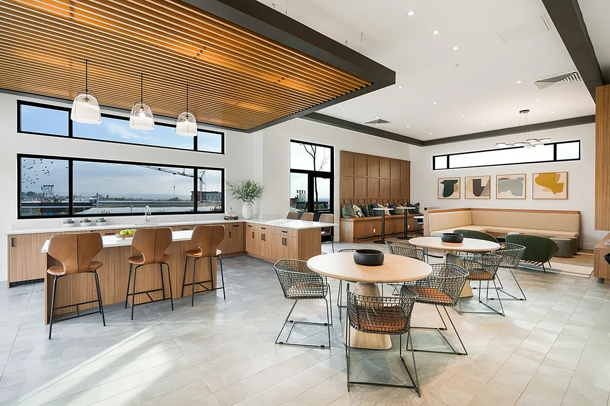 Modern clubroom at Cottonwood Highland featuring a sleek kitchen with bar seating, stylish open dining area, and panoramic window views.