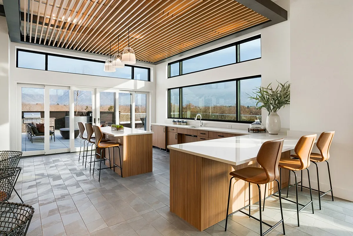 Modern open kitchen at Cottonwood Highland Apartments with high ceilings, large windows, and stylish wood accents offering stunning natural light and outdoor views.