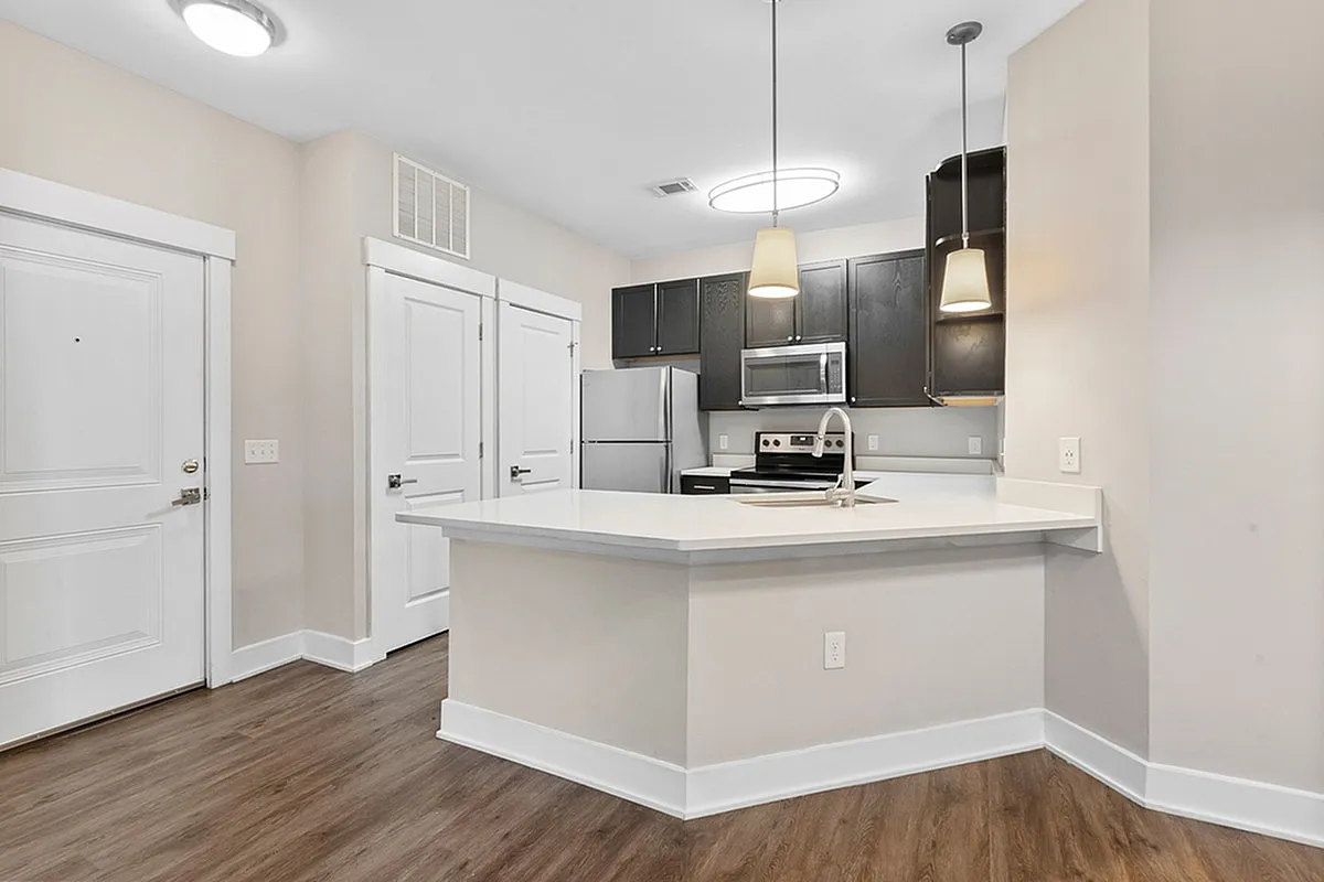 Modern kitchen at Cottonwood Reserve Apartments with sleek dark cabinets, stainless steel appliances, and elegant pendant lighting, featuring a spacious island and bright, open layout.