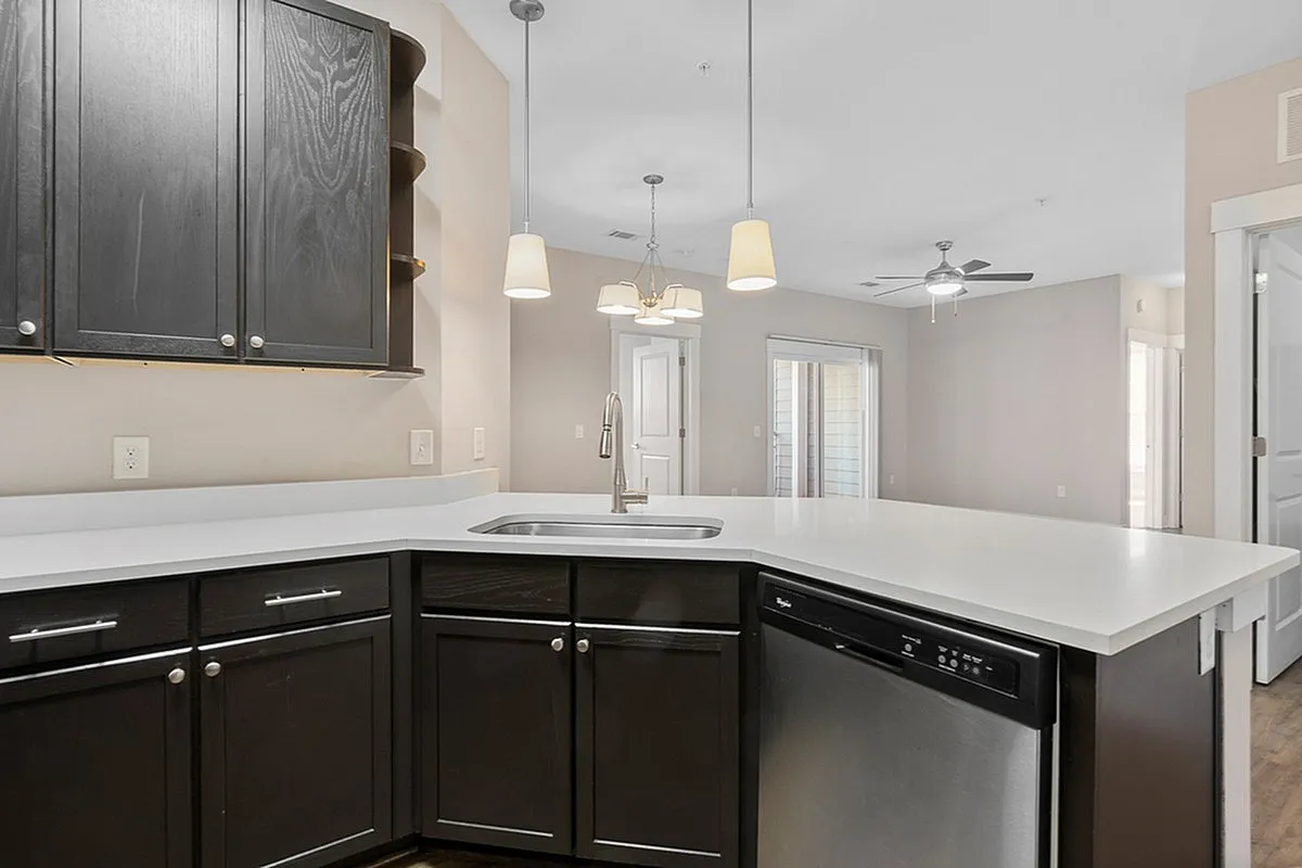Modern kitchen at Cottonwood Reserve Apartments with sleek dark cabinetry, stainless steel appliances, and elegant pendant lighting creating a spacious and inviting ambiance.