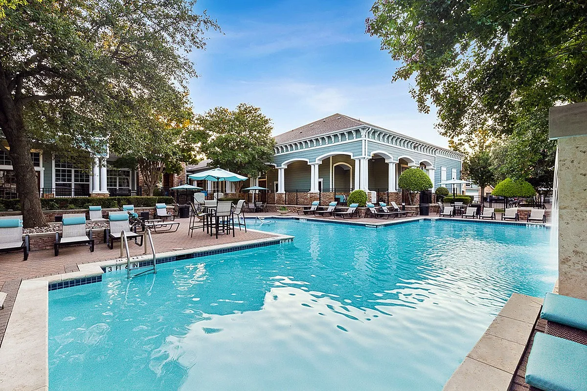 Inviting luxury poolside retreat at Cottonwood Ridgeview Apartments with elegant seating area, surrounded by lush greenery and modern architecture.