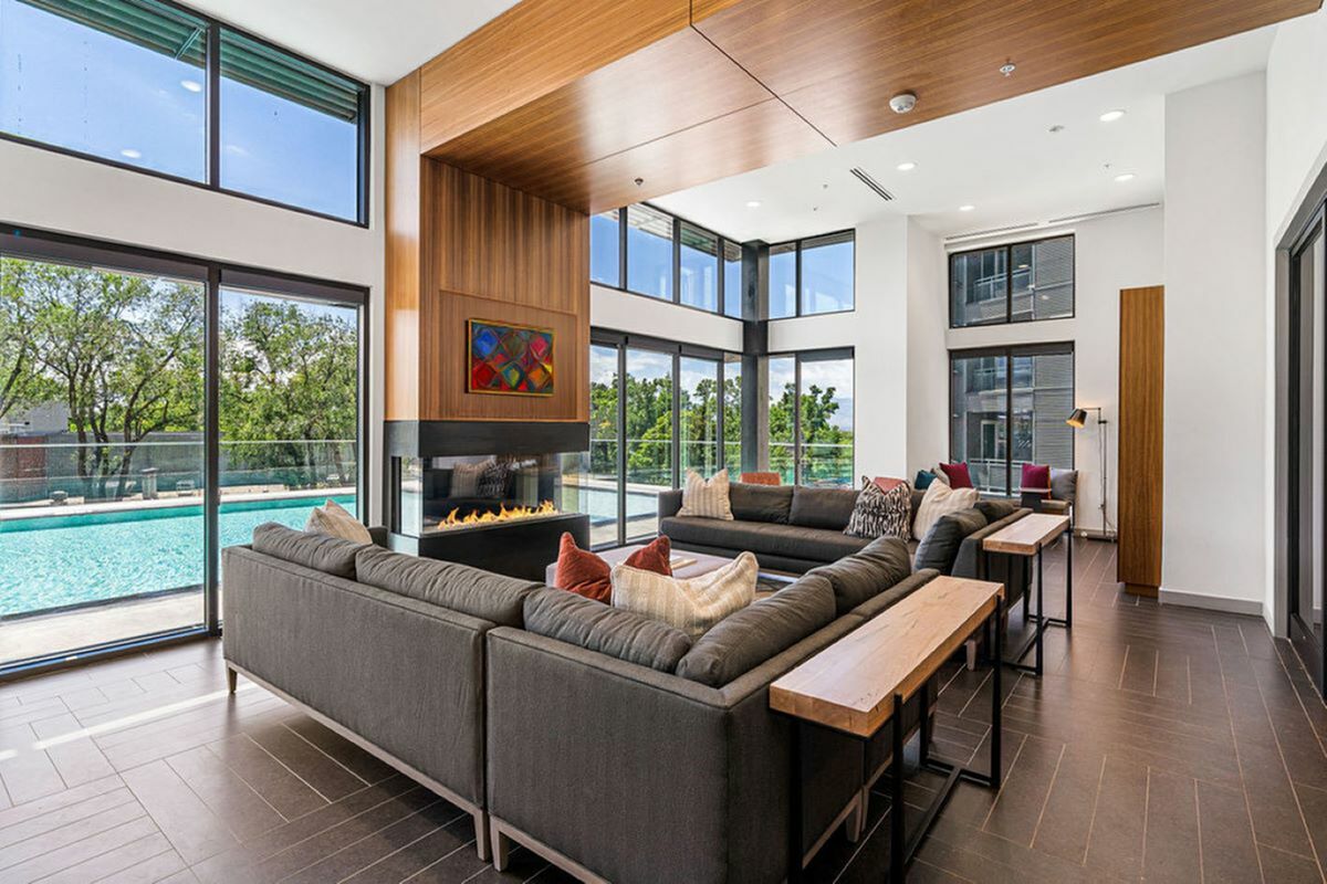 View of Sugarmont Clubroom Showing Wood Lining, Grey Couch and Tall Glass Windows Showing A Pool View