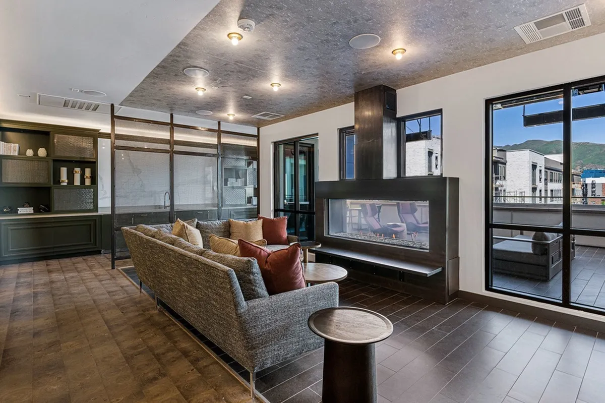 Elegant sky lounge living room with modern sectional sofa, ambient lighting, and sleek glass fireplace, offering mountain views at Sugarmont Apartments.
