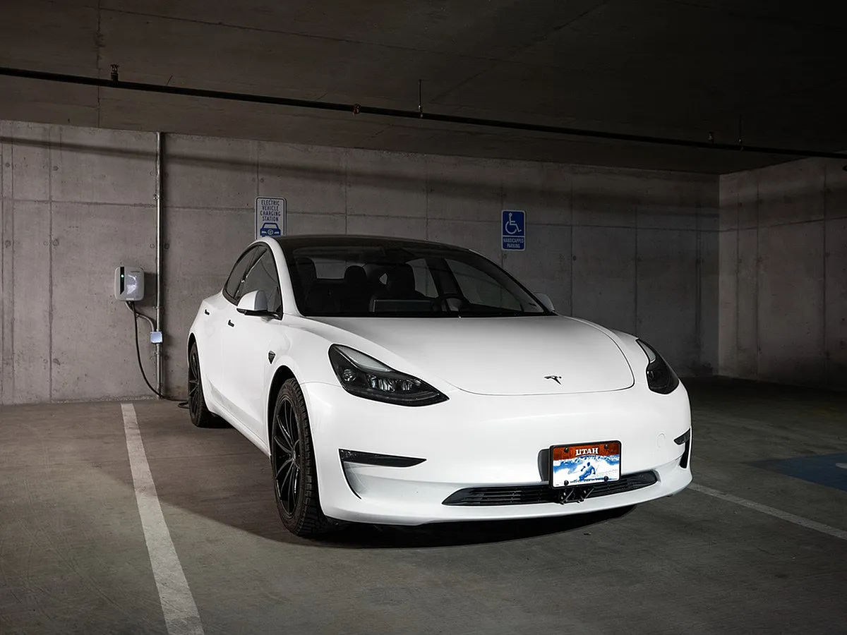 Sleek electric car parked in a modern garage at Sugarmont Apartments and Townhomes with convenient charging station, highlighting eco-friendly urban living.