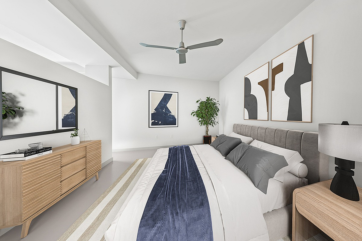 Elegant bedroom at Cottonwood Westside in Atlanta with modern decor, featuring a plush bed, stylish artwork, and a sleek ceiling fan.