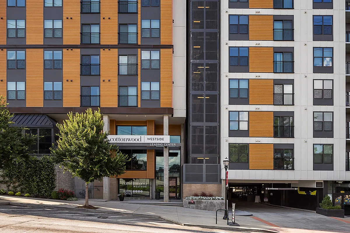 Modern urban apartment building, Cottonwood Westside, with stylish wood-panel design and inviting leasing center entrance.