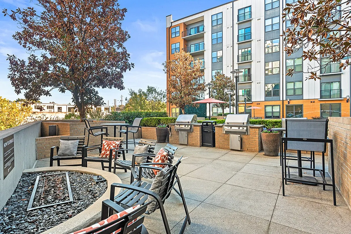 Inviting outdoor patio at Cottonwood Westside Apartments with stylish seating, modern grills, and lush greenery, perfect for entertaining.