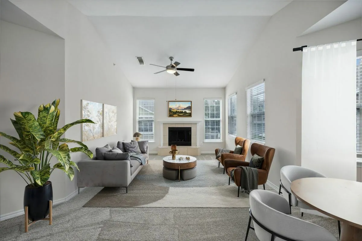 Bright, spacious living room with modern decor, featuring a cozy gray sofa, elegant brown armchairs, and a chic marble coffee table; large windows with captivating natural light at Cottonwood Ridgeview Apartments in Plano