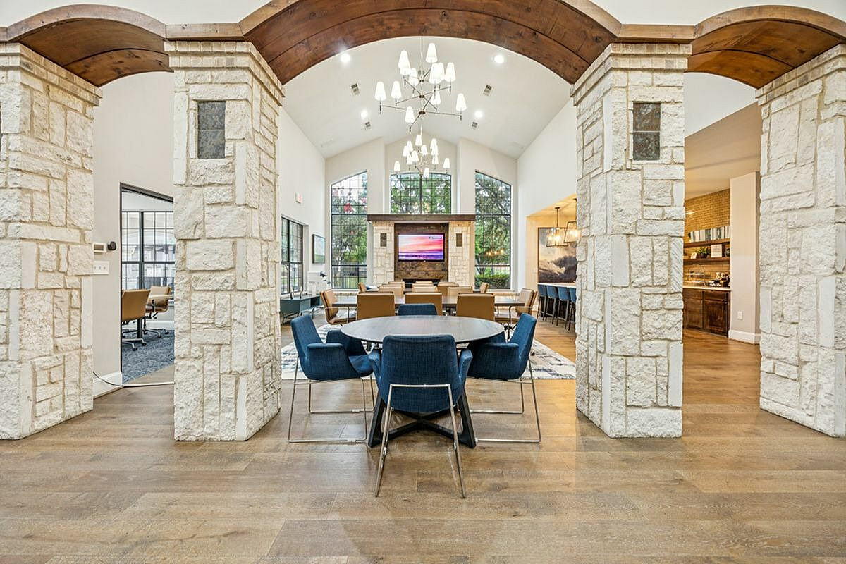 Elegant coworking space with stone archways, modern seating, and natural light flooding through large windows at Apt CoWork at Toscana at Valley Ridge Apartments in Lewisville