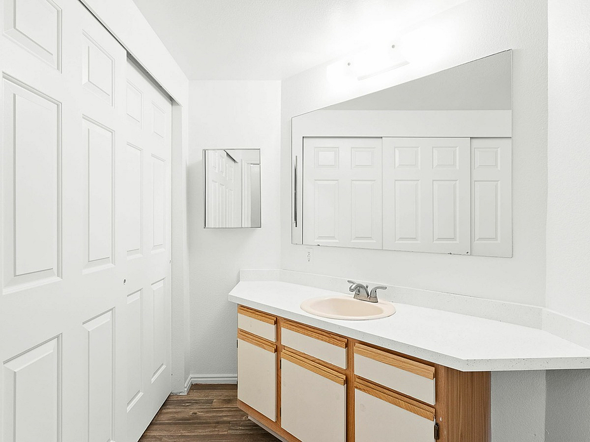 Bright and modern bathroom Fox Point in Old Farm Apartments with elegant white cabinetry, large mirror, and sleek countertop, offering a refreshing and clean ambiance.