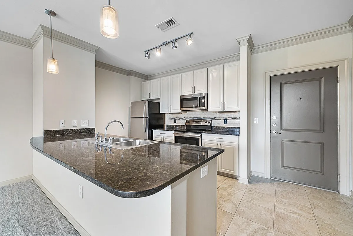 Contemporary kitchen at Heights at Meridian Apartments with sleek granite countertops, stainless steel appliances, and elegant pendant lighting.