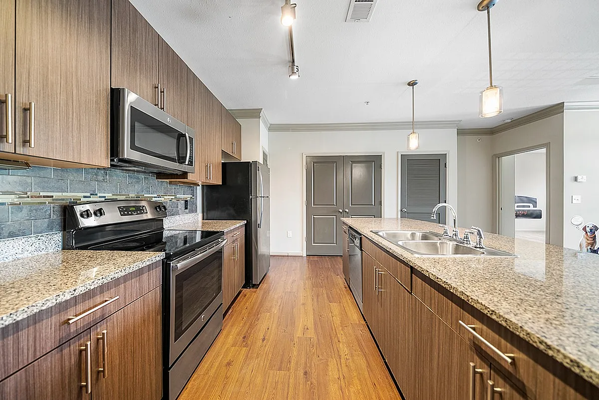 Modern kitchen at Heights at Meridian Apartments with sleek dark wood cabinetry, stainless steel appliances, and granite countertops, exuding contemporary elegance.