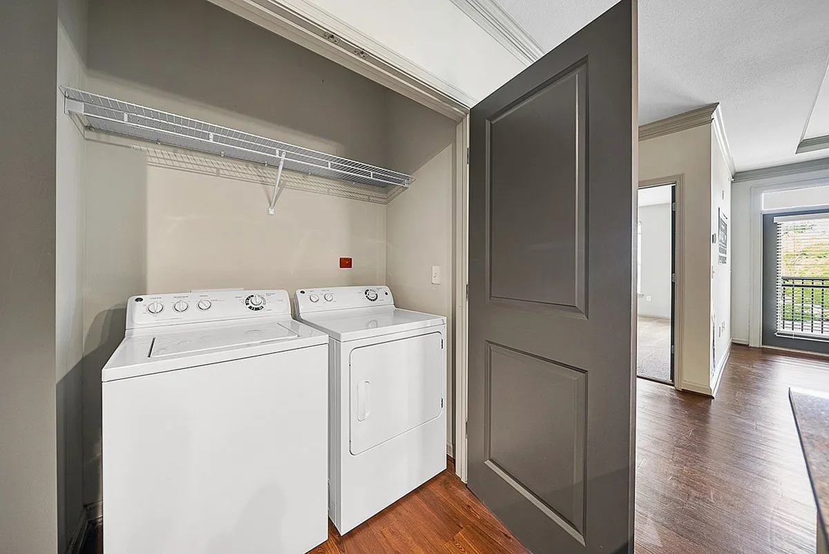 Modern apartment at Heights at Meridian with in-unit laundry featuring a sleek washer and dryer, complemented by stylish wooden flooring and a spacious hallway.