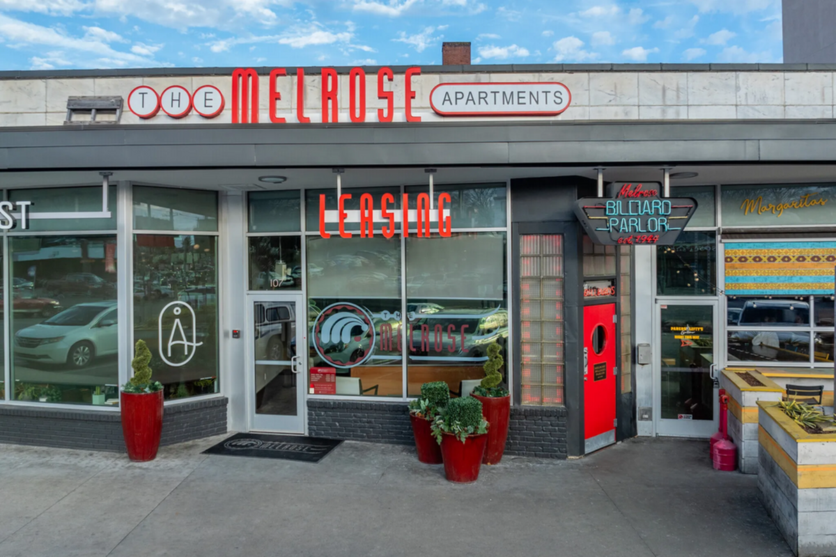 Vibrant Melrose Apartments entrance featuring bold signage and welcoming atmosphere with lush greenery and a retro billiard parlor in Berry Hill, Tennessee.