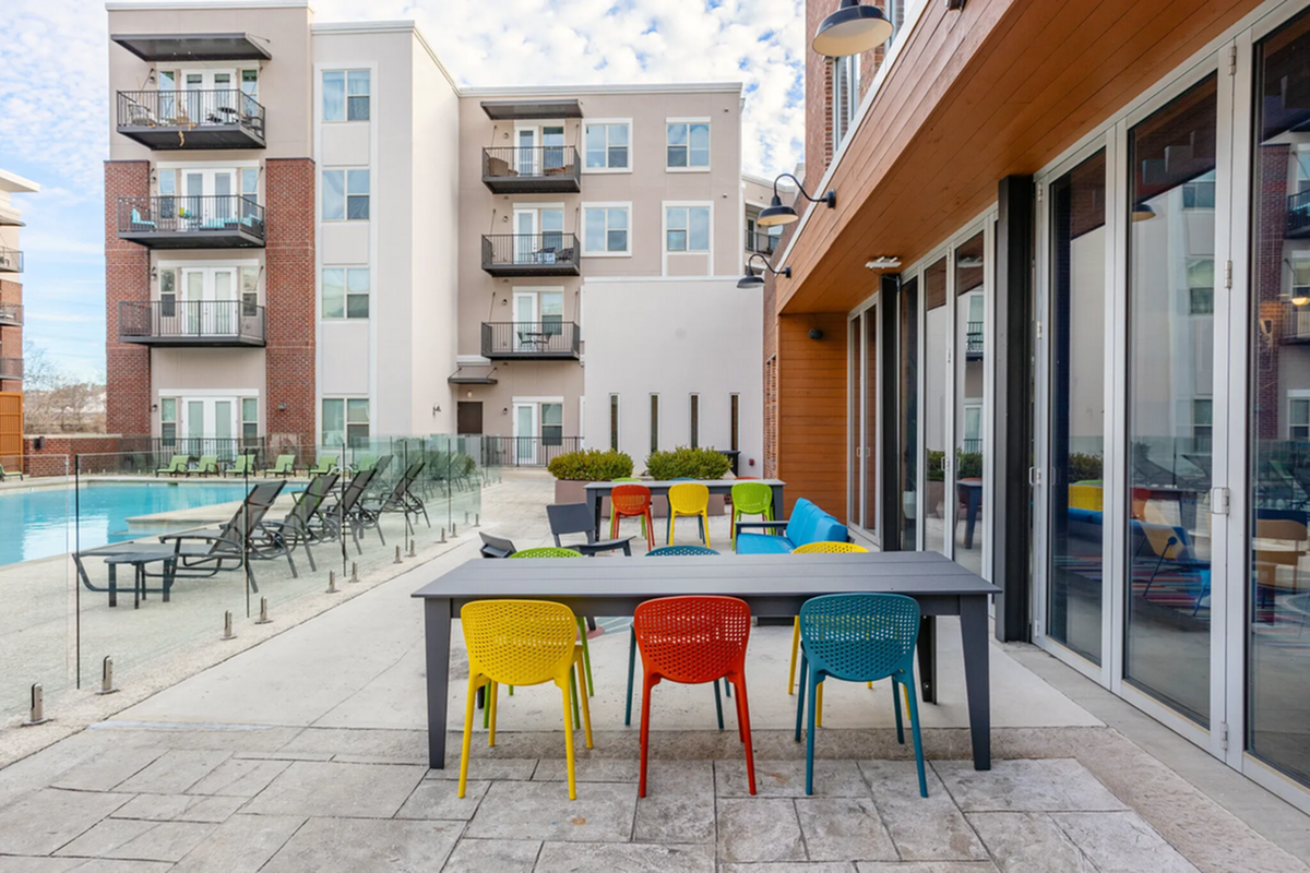 Chic outdoor communal space featuring a modern pool, and vibrant seating at The Melrose Apartments.