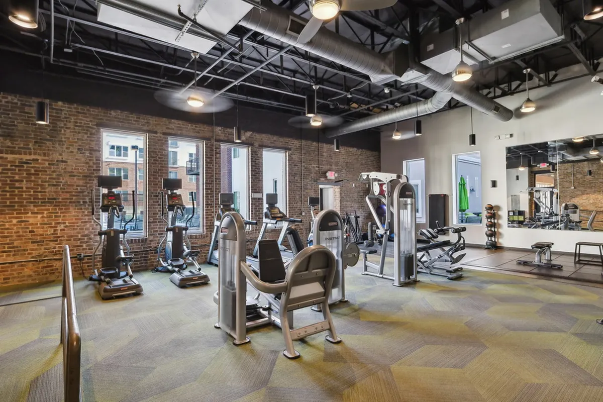 Chic industrial-style fitness center with modern equipment and exposed brick walls, offering a dynamic workout environment at The Melrose Apts in South Nashville.
