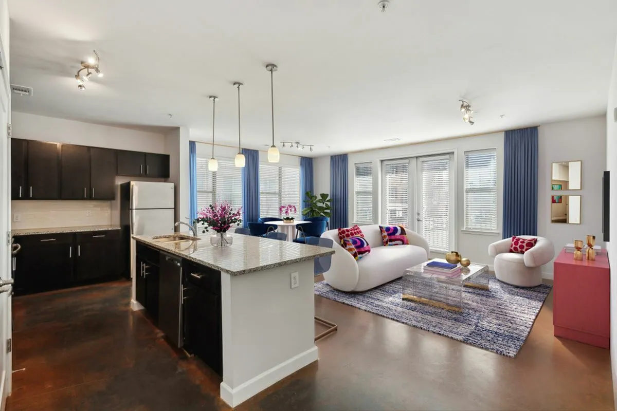 Modern open-concept 2 bedroom living space featuring a stylish kitchen island, elegant dining area, and cozy living room with vibrant decor and natural light at The Melrose Apartments in Nashville,TN.