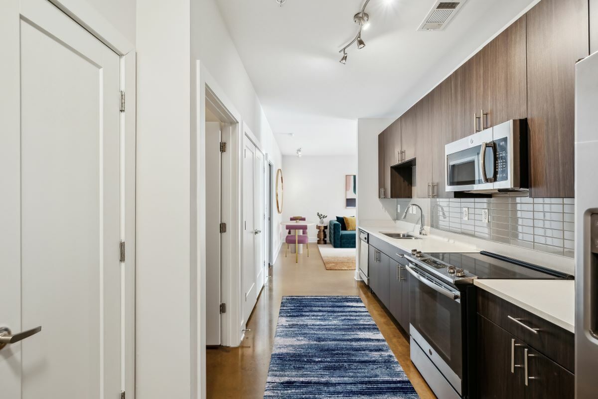 Modern open-concept kitchen with sleek cabinetry, stainless steel appliances, and a stylish living area view at The Melrose Apts in Berry Hill, Tennessee.
