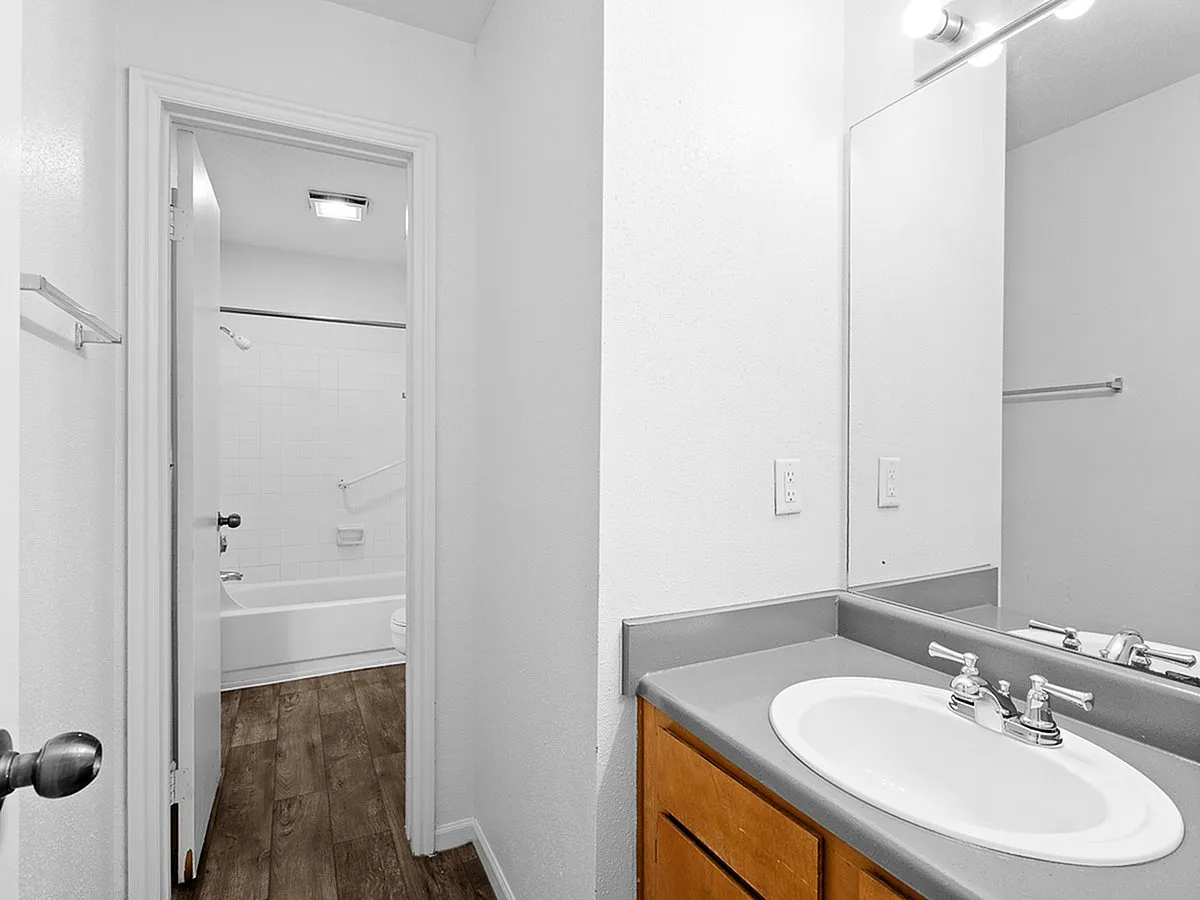 Sleek modern bathroom at Cottonwood Apartments with elegant vanity, spacious sink, and bright lighting inviting a fresh ambiance.