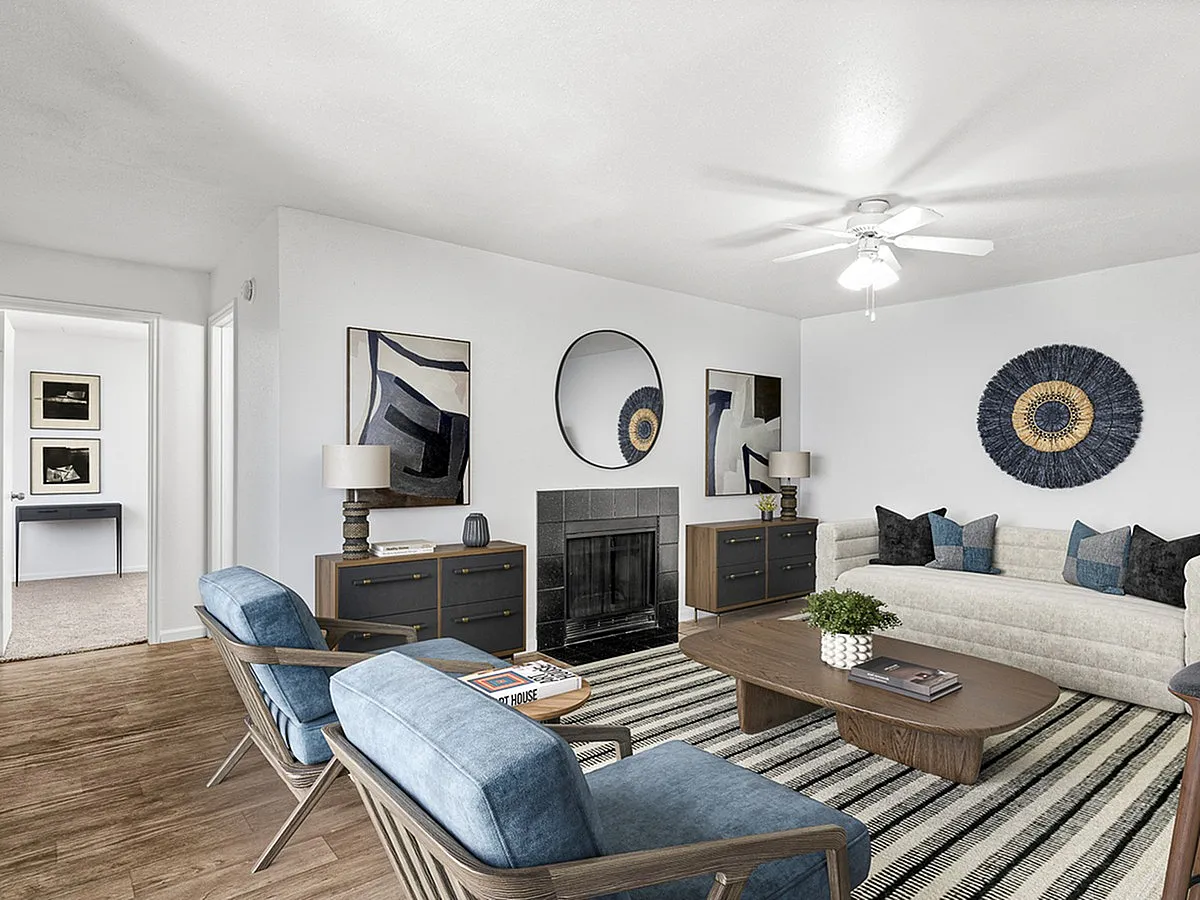 Elegant living room at Cottonwood Apartments with modern decor, featuring plush seating, stylish artwork, wooden furniture, and a cozy fireplace.
