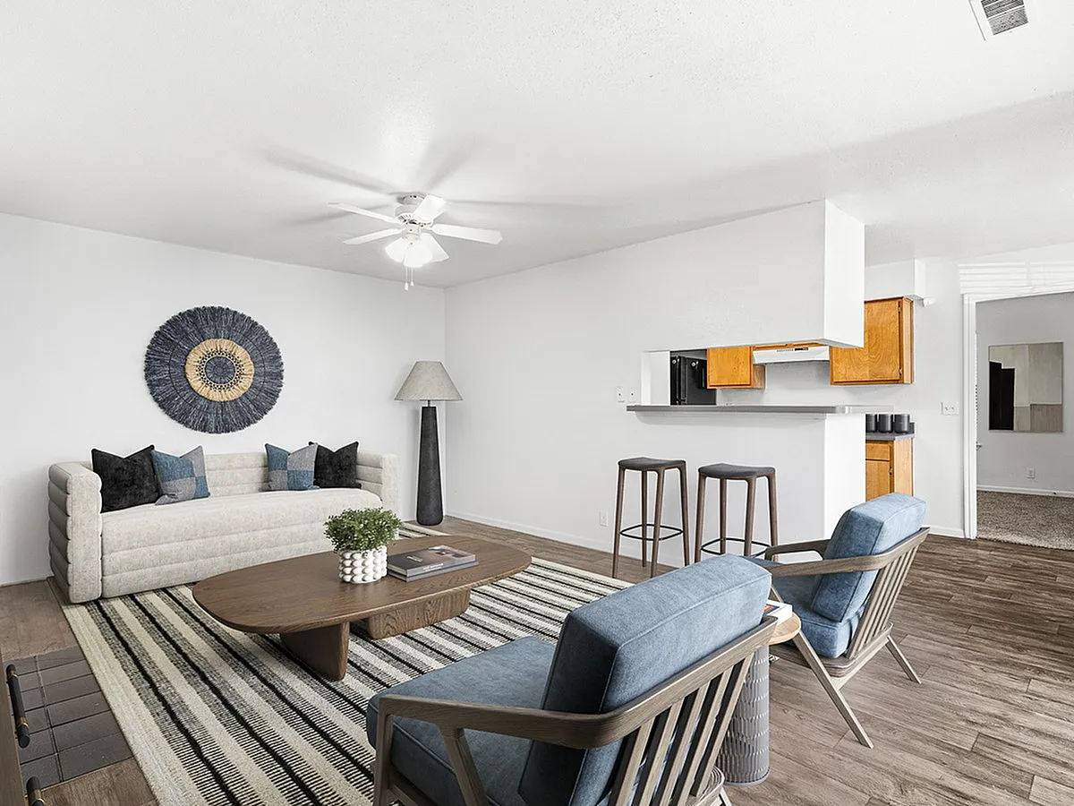 Chic open-concept living room at Cottonwood Apartments with modern decor, cozy seating, and a stylish kitchen breakfast bar.