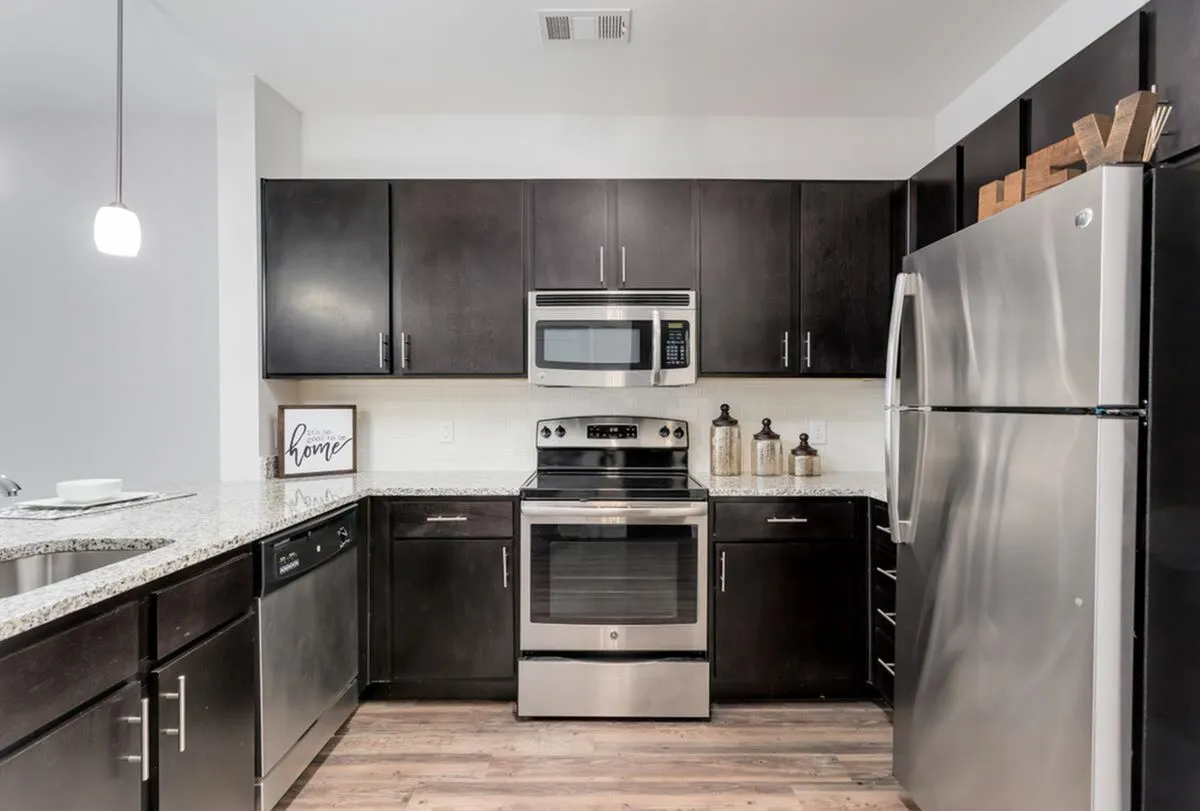Sleek modern kitchen featuring dark cabinetry, stainless steel appliances, and elegant granite countertops at The Melrose Apartments in Nashville.