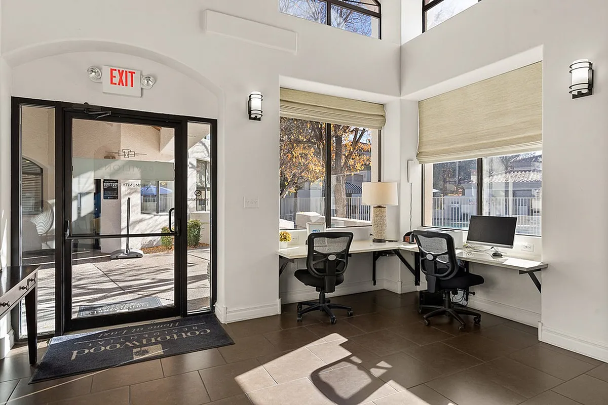Bright and inviting office space at Pavilions Apartments with modern desks, large windows, and stylish decor.