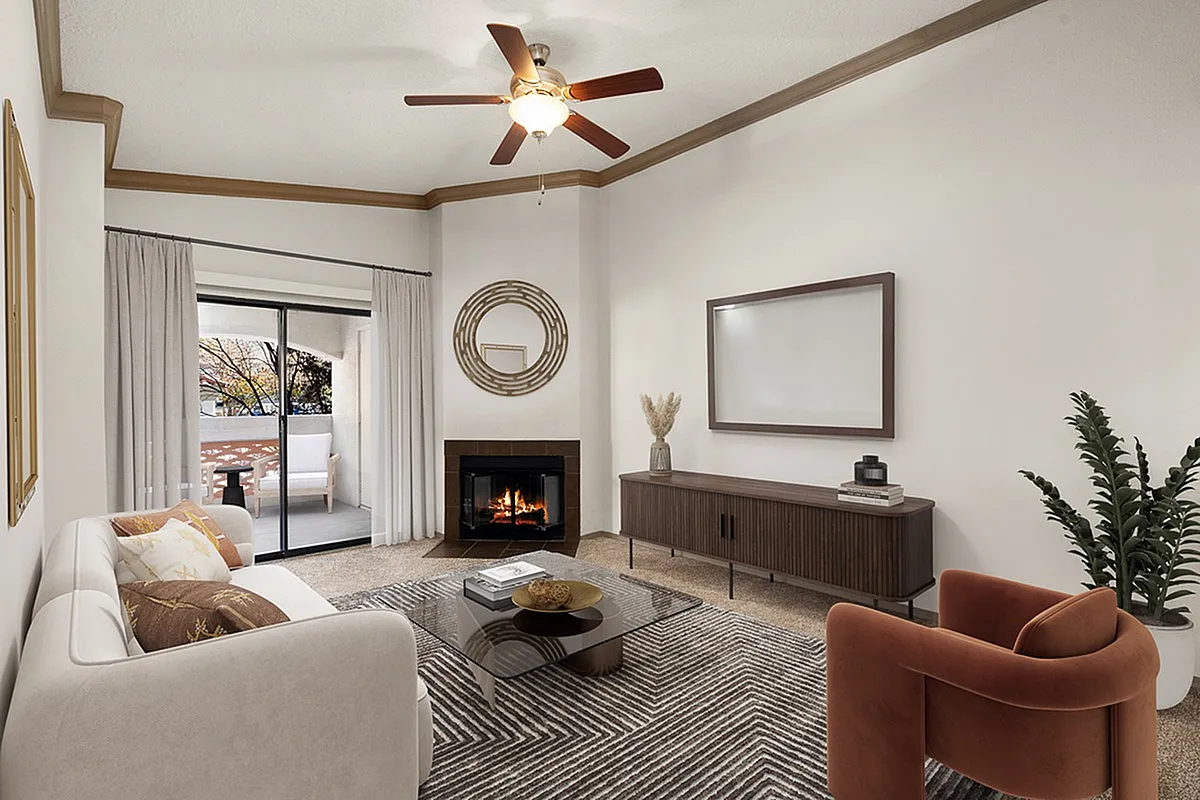 Inviting living room at Pavilions Apartments with elegant decor, featuring a cozy fireplace, stylish furniture, and a serene balcony view.