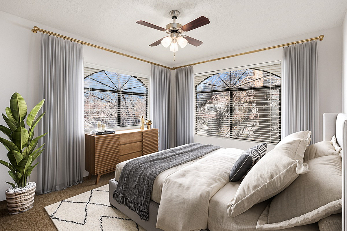 Bright and inviting bedroom at Pavilions Apartments featuring elegant decor, large windows with stylish curtains, and a cozy bed perfect for relaxation.