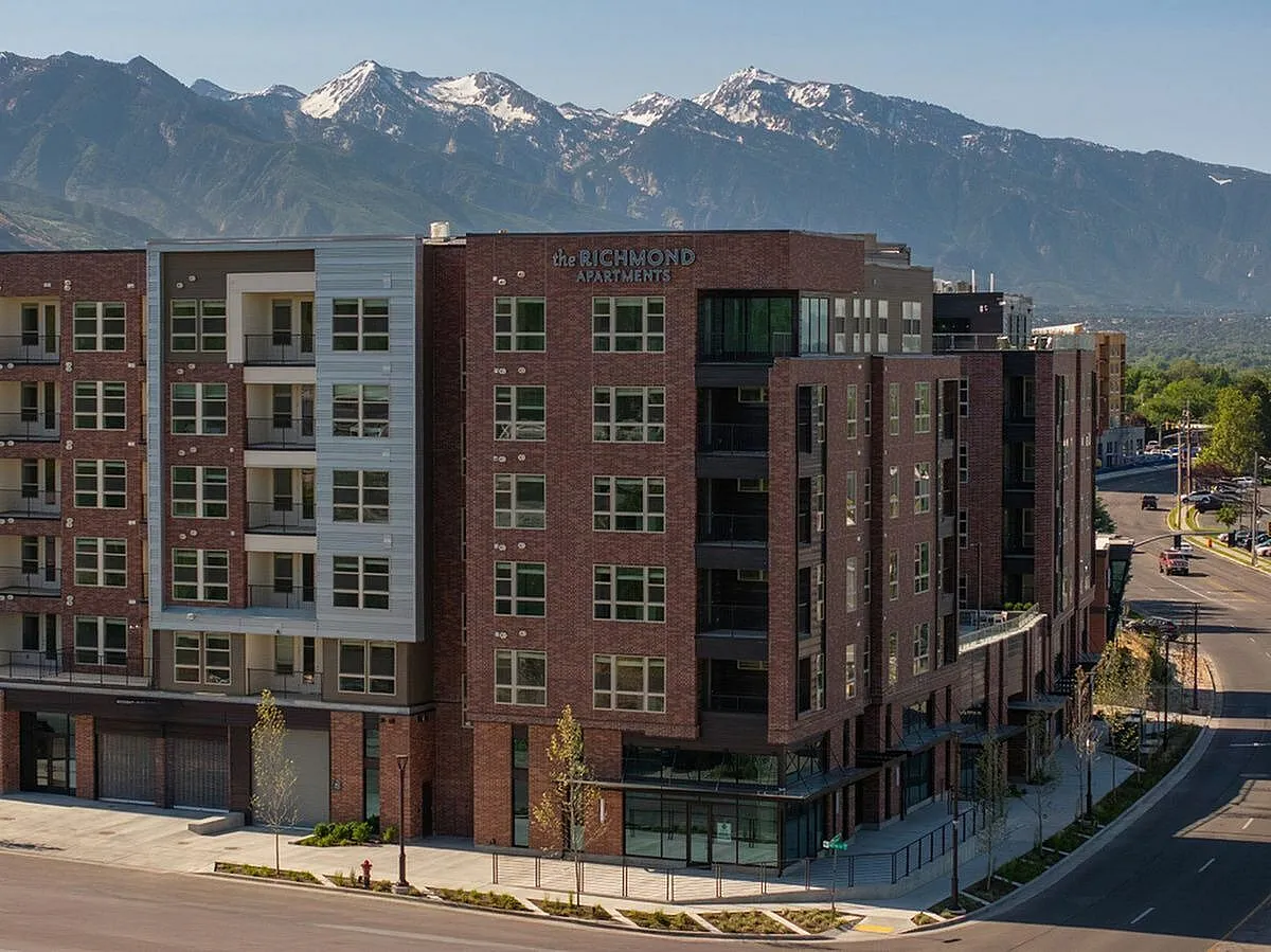 Modern apartment complex with stunning mountain views, featuring stylish brick facade and large windows for natural light at The Richmond Apartments in Millcreek