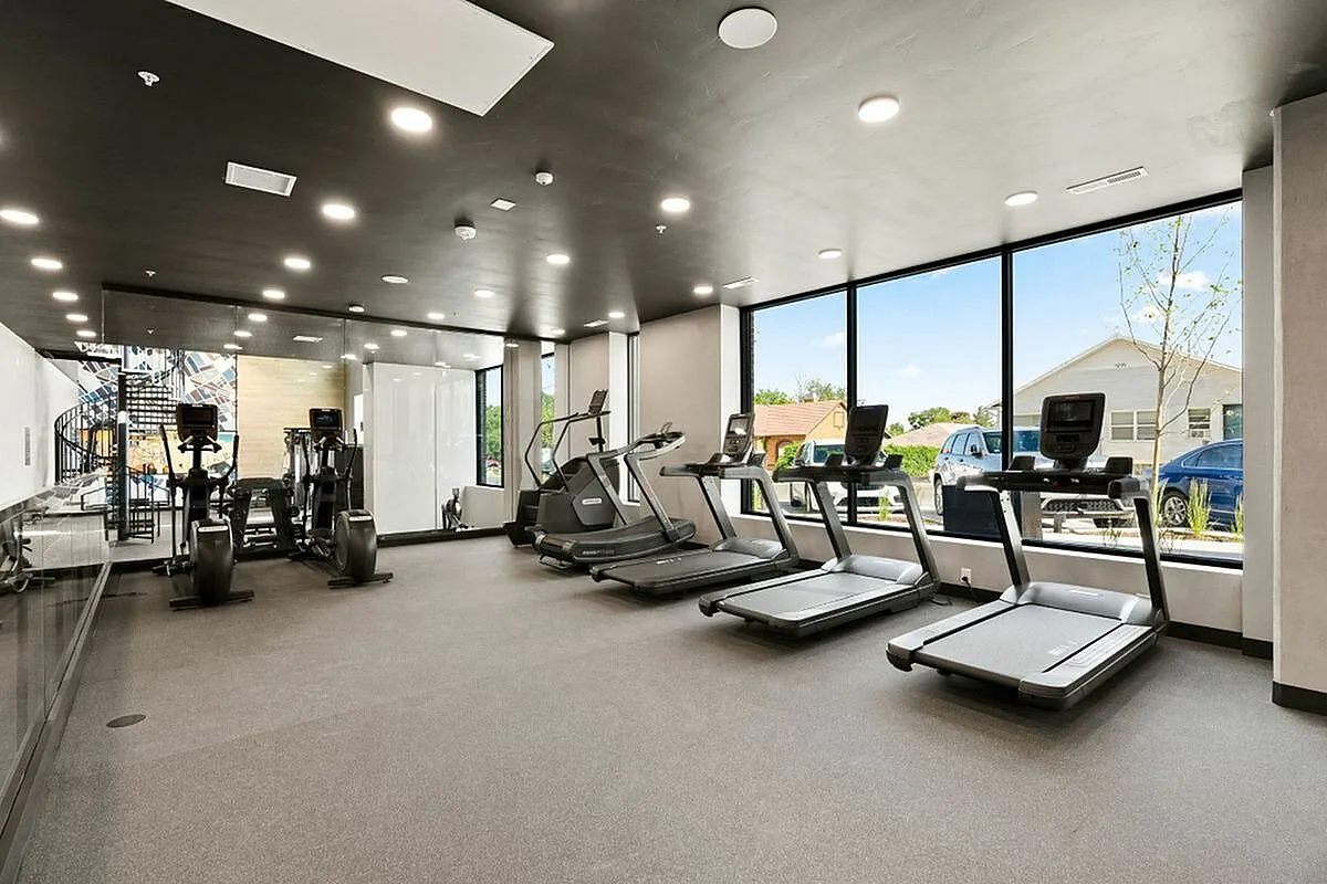 Bright and modern fitness center featuring state-of-the-art treadmills and exercise equipment with large windows for natural light at The Richmond Apartments in Millcreek Utah