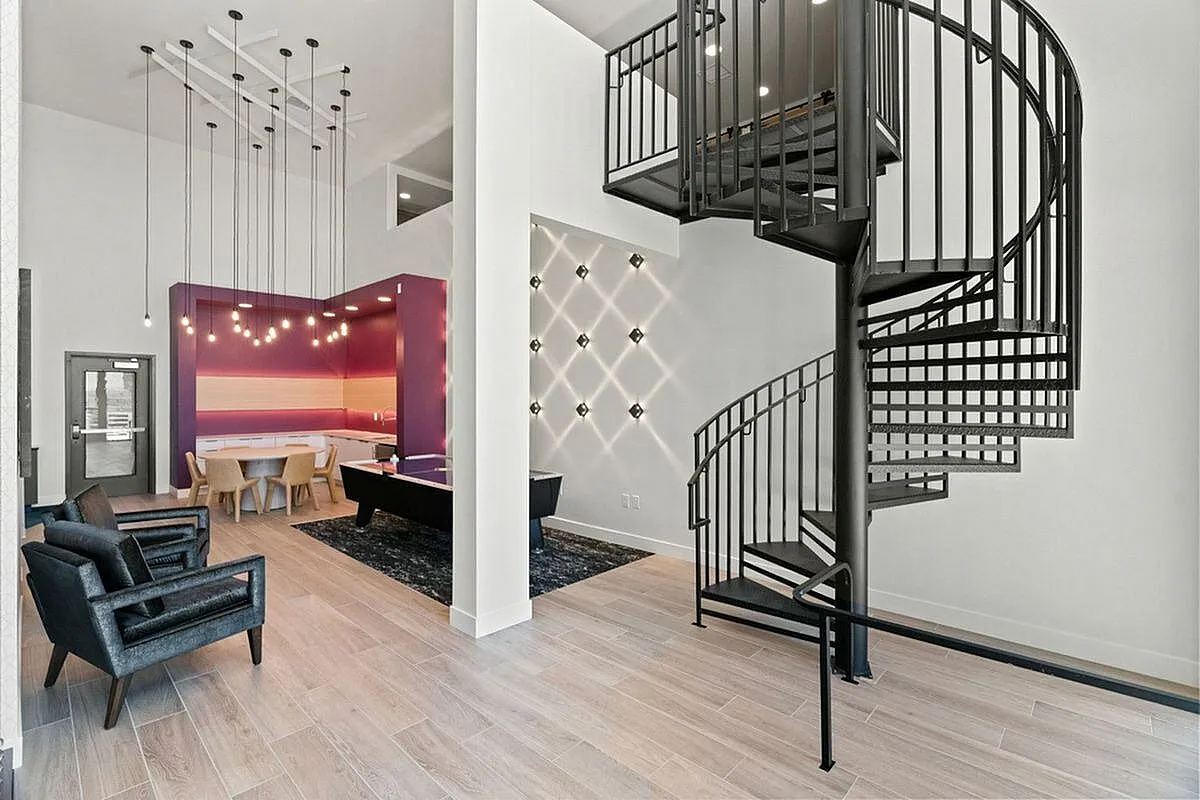 Clubroom featuring a striking spiral staircase, elegant pendant lighting, and a vibrant dining nook with artistic wall accents at The Richmond Apartments in Salt Lake City Utah