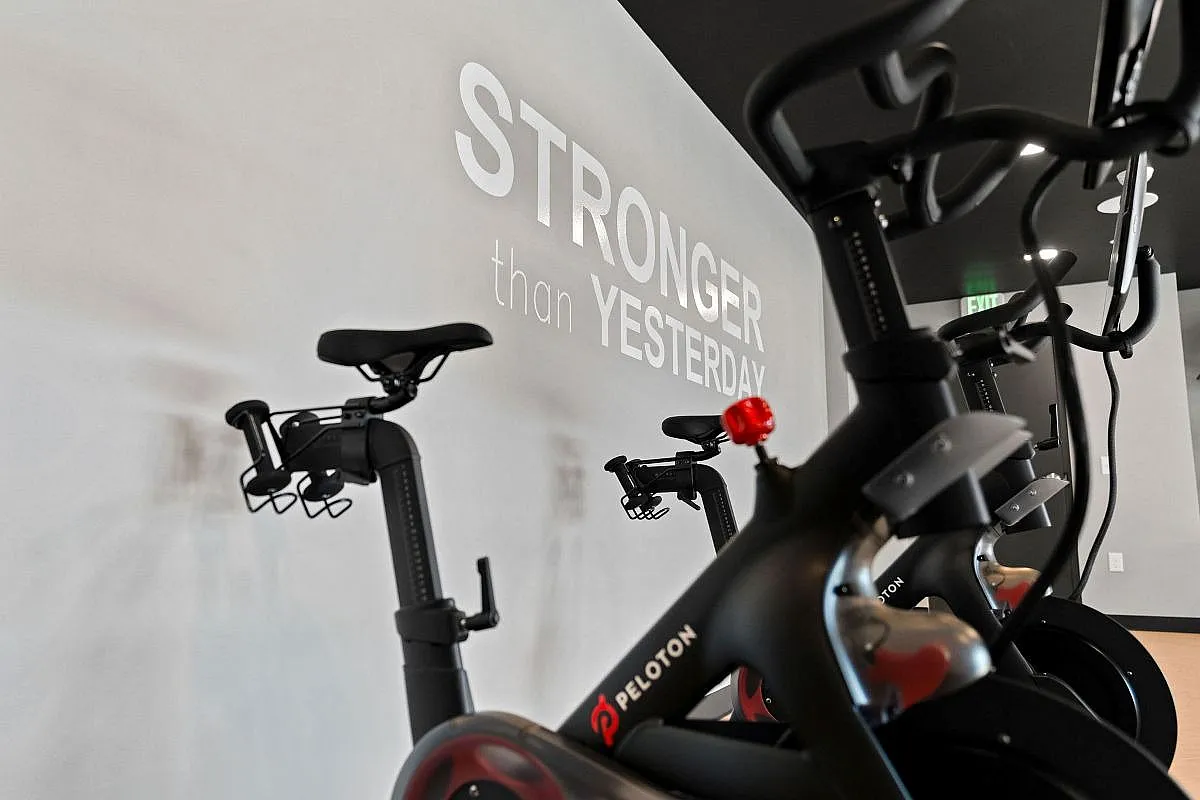 Modern workout room featuring Peloton bikes with motivational 'Stronger than Yesterday' wall art at The Richmond Apartments in Millcreek