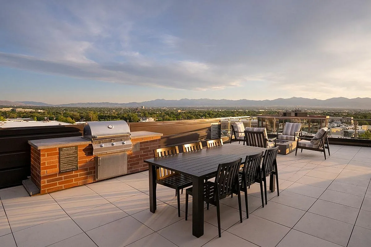 Expansive rooftop terrace with modern grill, elegant dining area, and stunning mountain views at The Richmond Apartments in SLC Utah