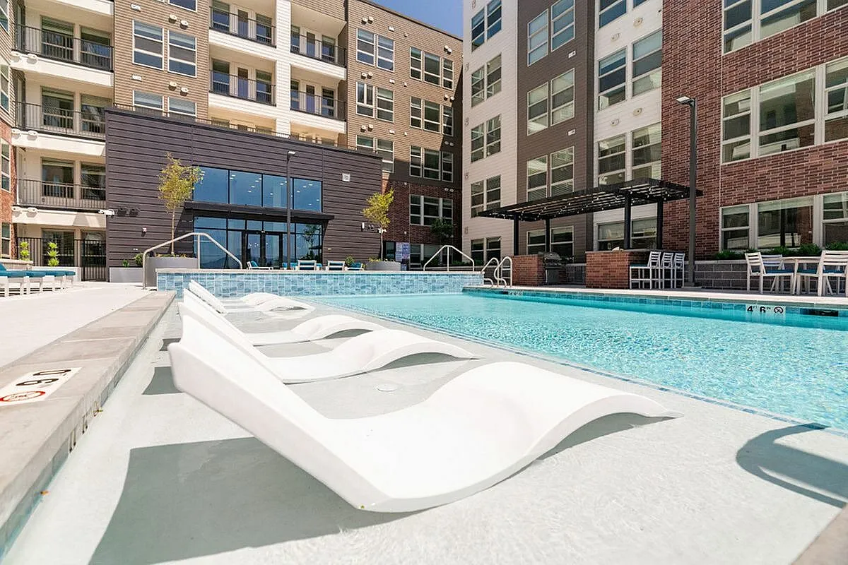 Luxurious apartment complex with a stunning outdoor swimming pool featuring stylish deck chairs and modern architecture at The Richmond Apartments in Salt Lake City Utah